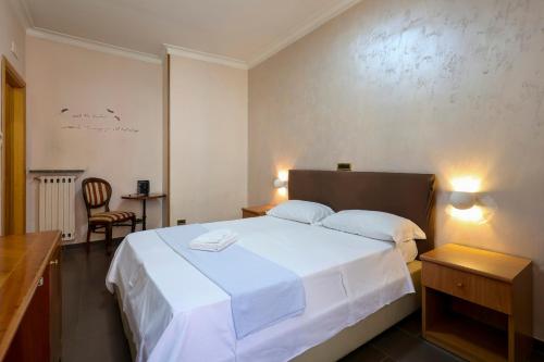 a bedroom with a large white bed and a chair at Hotel Cesare 14 in Naples