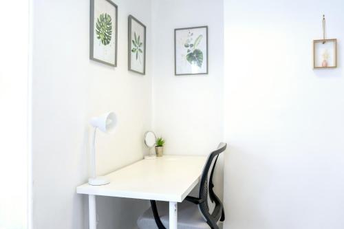 a white desk with a lamp and pictures on the wall at Modern Cozy Flat with Great Location in Bletchley