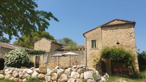 a building with an umbrella and a stone wall at Mas des Pelissiers Gîte in Sabran