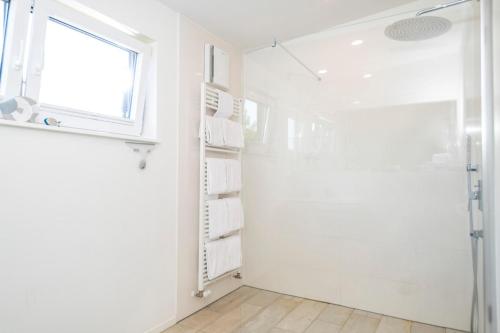 a white bathroom with a shower and a window at Insel in Gelting