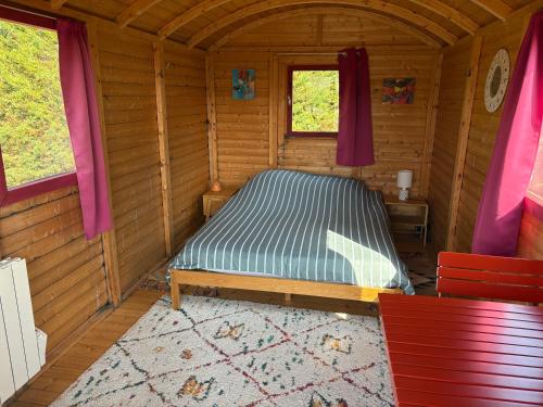 een slaapkamer met een bed in een houten hut bij Terres du Calvados 