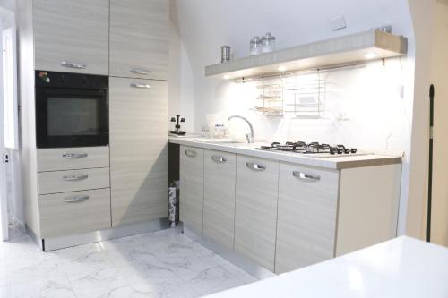 een witte keuken met een spoelbak en een fornuis bij Corte Cosi&Mia Centro storico in Gallipoli