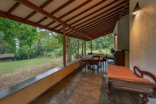 a covered porch with tables and chairs and a field at WildEscape, Yala Blocks 3 & 5 in Buttala