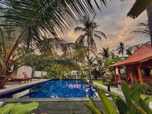 ein Swimmingpool vor einem Haus mit Palmen in der Unterkunft mata villas gili trawangan in Gili Trawangan