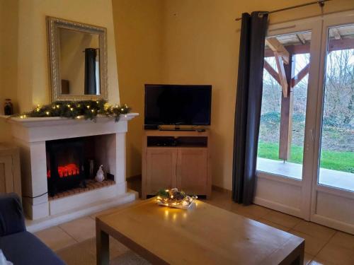 a living room with a fireplace and a television at Spacious villa with garden and pool in Les Forges