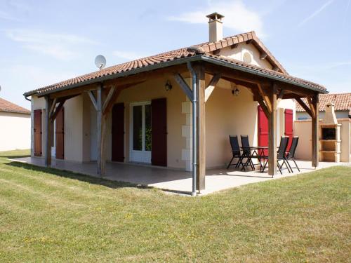 a pavilion with chairs and a table in front of a house at Spacious villa with garden and pool in Les Forges
