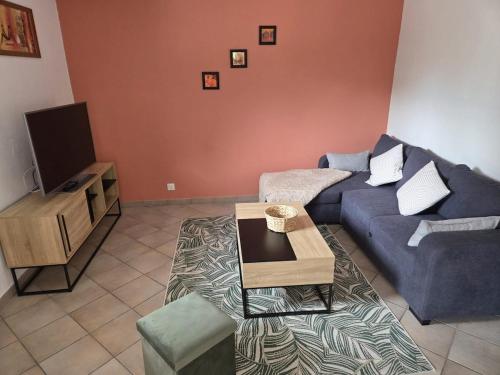 a living room with a blue couch and a table at Appartement avec terrasse au pied des cols et des stations de ski in Villargondran