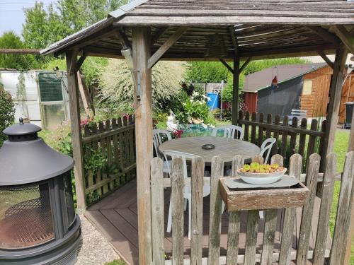 un gazebo en bois avec une table et un bol de fruits dans l'établissement Côté jardin, 