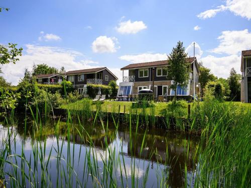 a house with a pond in front of it at Comfortable family and friends house with wellness in Vlagtwedde