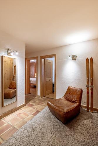 a living room with a leather chair and a mirror at Ride Inn Verbier - B&B - private small twin room, shared bathrooms in Verbier