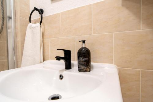 a bathroom sink with a bottle of soap on it at Modern Cozy Flat with Great Location in Bletchley