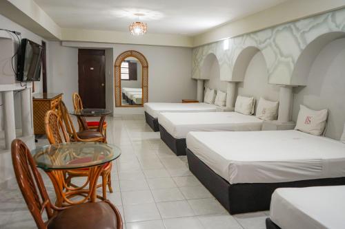 a hotel room with four beds and a table and a tv at OYO Hotel Santander Veracruz Centro Historico in Veracruz