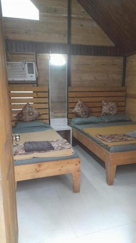 two beds in a wooden room at Nature Glamping in Matheran