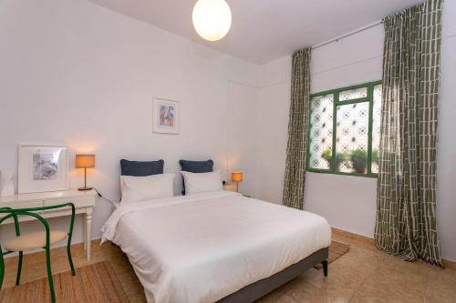 a bedroom with a bed and a desk and a window at Two Bedroom Garden Cottage in Quiet Street in Limassol