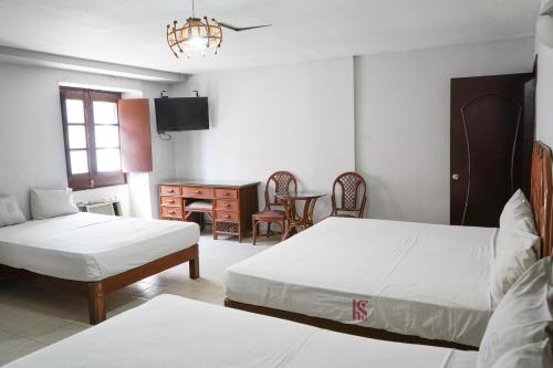 a bedroom with two beds and a table and a desk at OYO Hotel Santander Veracruz Centro Historico in Veracruz