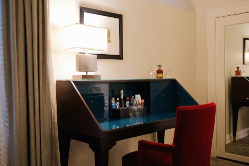 a desk in a hotel room with a red chair at The Oxford Hotel in Denver