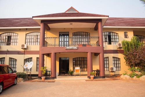 a building with a red car parked in front of it at Hapuwani Village Lodge in Mulanje