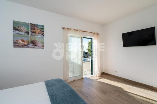 a white room with a tv and a bed at Villa Sunset Lovers in Alcantarilha