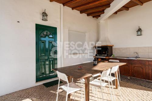 a dining room with a wooden table and chairs at Villa Sunset Lovers in Alcantarilha