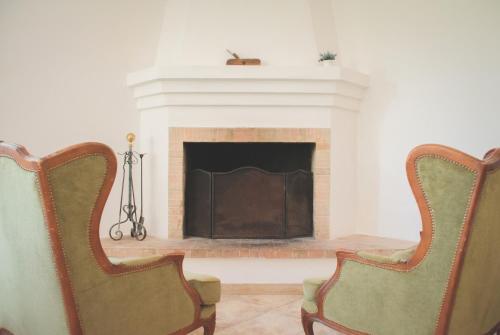 two chairs in a living room with a fireplace at Ad un passo da Cisternino - Trulli con Camino, Foresta e BBQ in Cisternino