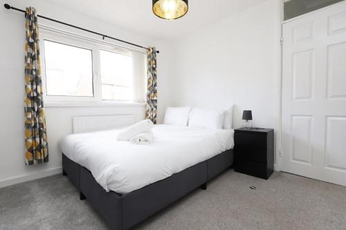 a bedroom with a large bed with a window at Lovely 3-Bed in Scenic Aberdare! in Aberdare