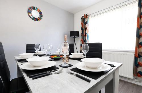 a dining room table with white plates and wine glasses at Lovely 3-Bed in Scenic Aberdare! in Aberdare