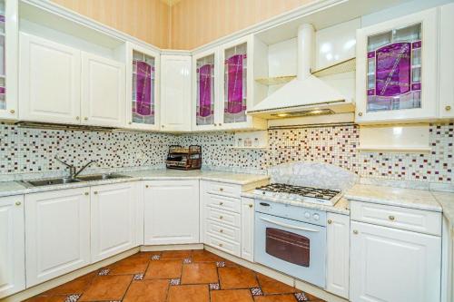 a kitchen with white cabinets and a stove top oven at Four seassons apartment in Baku