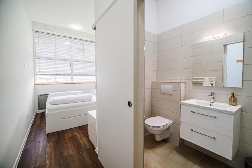 a white bathroom with a toilet and a sink at Comfort Rooms Obrežje by Highway, Free Covered Parking in Jesenice na Dolenjskem