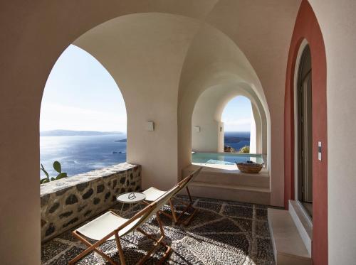 a room with two chairs and a view of the ocean at Villa Bordeaux in Fira