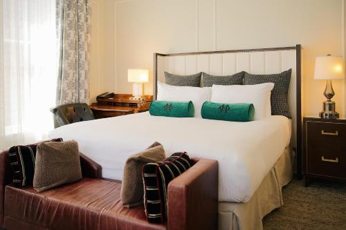 a bedroom with a large white bed with green pillows at The Oxford Hotel in Denver