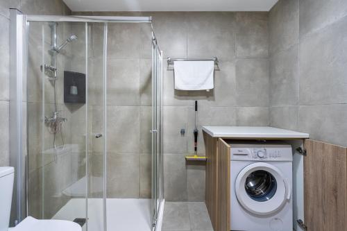 a bathroom with a shower and a washing machine at Invictus 2-Bedroom Apartment in Larnaca