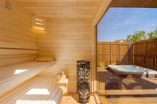 a sauna with a tub and a window at Natur Harmony Tiszafüred in Tiszafüred