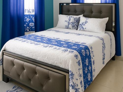 a bed with blue and white sheets and pillows at Villa Rosa in San Felipe de Puerto Plata
