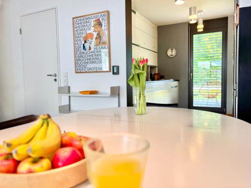 a table with a bowl of fruit and a glass of orange juice at Snug Stays 7 - Design House in Starnberg, Terrace, Lake, Munich south in Starnberg