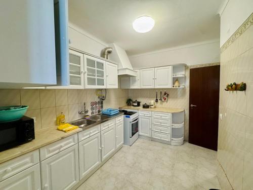 una cucina con mobili bianchi e un lavandino di Casa de Sintra a Sintra