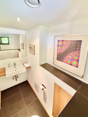 a bathroom with a sink and a painting on the wall at Snug Stays 7 - Design House in Starnberg, Terrace, Lake, Munich south in Starnberg