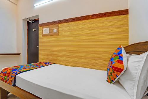 a bedroom with a bed with a wooden headboard at FabHotel Raja Residency in Alāndurai