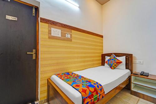 a small bedroom with a bed with a wooden headboard at FabHotel Raja Residency in Alāndurai