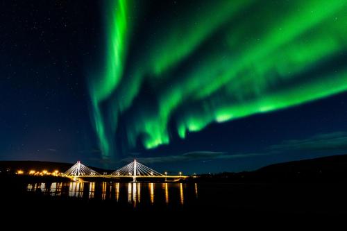 an aurora over a bridge over water at night at Utsjoki Arctic Resort in Utsjoki