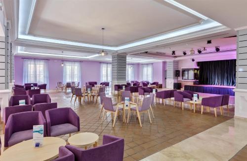 a dining room with purple chairs and tables and tablesktop at Barceló Isla Canela in Isla Canela