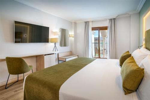 a hotel room with a large bed and a desk at Barceló Isla Canela in Isla Canela