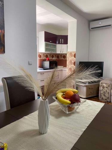a vase with a bowl of fruit on a table at Apartmani Milojić in Soko Banja