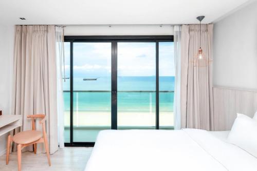 a bedroom with a bed and a view of the ocean at Zand Morada Pattaya in Jomtien Beach