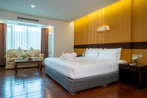 a hotel room with a large bed and a couch at Khum Phucome Hotel -SHA Extra Plus in Chiang Mai
