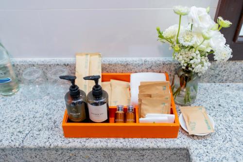 an orange tray with bottles of soap and a vase of flowers at Khum Phucome Hotel -SHA Extra Plus in Chiang Mai