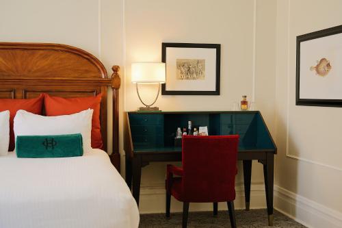 a bedroom with a bed and a desk with a bed and a chair at The Oxford Hotel in Denver