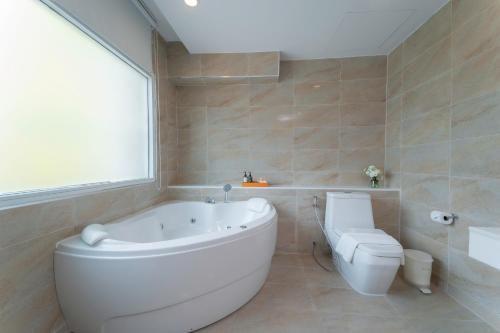 a bathroom with a large white tub and a toilet at Khum Phucome Hotel -SHA Extra Plus in Chiang Mai