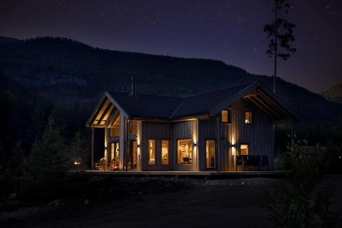 a house at night with the lights on at Saga Hytte | 6p | With Sauna, Hot Tub & Water View in Sinnes