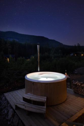 a bath tub sitting on a deck at night at Saga Hytte | 6p | With Sauna, Hot Tub & Water View in Sinnes