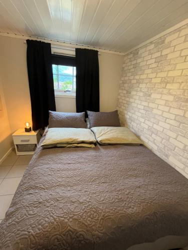 a large bed in a bedroom with a brick wall at Sjøhus med en praktfull utsikt in Bodø